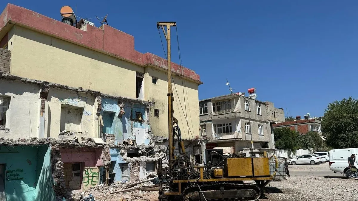 Yıkım aşamasındaki hasarlı yapının yanında paletli sondaj makinesi